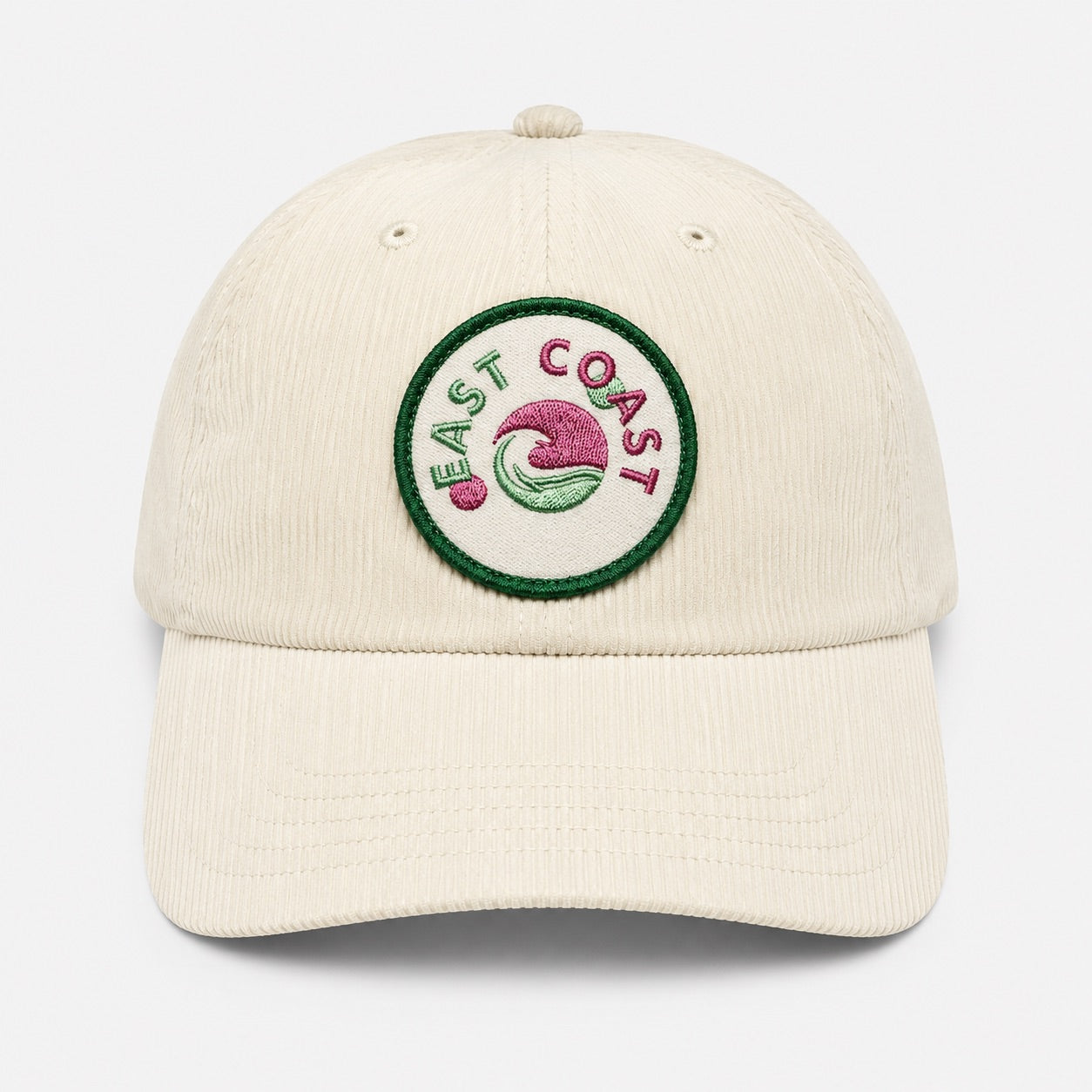 An off-white corduroy baseball cap featuring a circular embroidered 'East Coast' logo patch on the front, set against a clean light gray background.