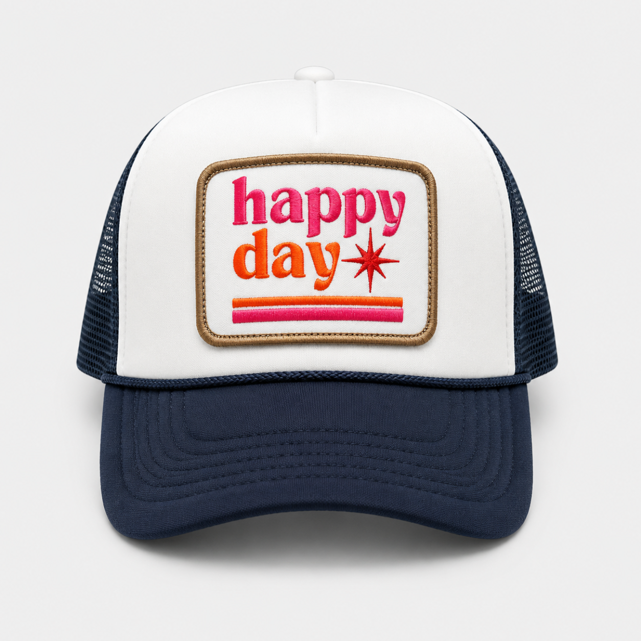 A white and navy blue trucker hat with a rectangular patch on the front that reads 'happy day' in pink and orange lettering with a starburst detail, shown against a light gray background.