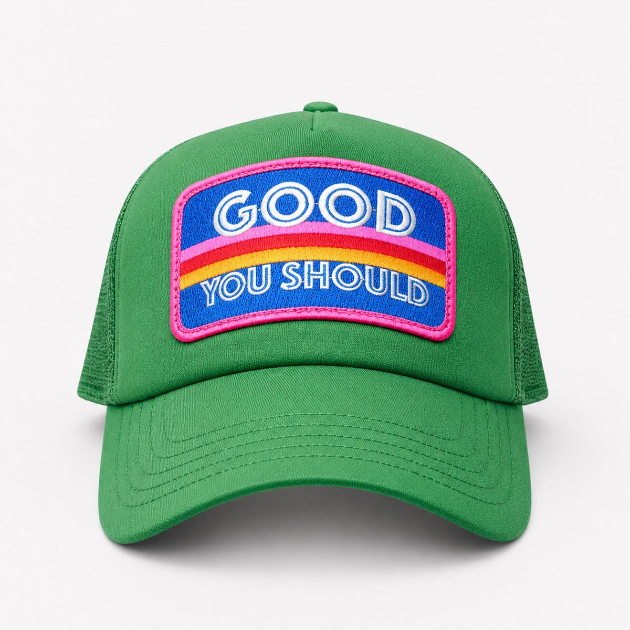 A green trucker-style cap with a curved brim and a colorful front patch that reads 'GOOD YOU SHOULD' in white text over blue, yellow, and red stripes with a pink border.